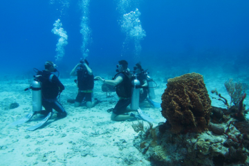 group of scuba divers sitting on sea floor in a circle